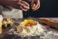 Hands breaking egg into raw dough on wooden table Royalty Free Stock Photo
