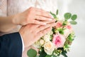 Hands of the bride and groom close up, wearing white gold wedding rings on her hands, the bride is holding a wedding bouquet of Royalty Free Stock Photo