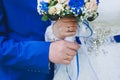 Hands of the bride and groom closeup holding a wedding bouquet of cream roses, blue chrysanthemums and white flowers. Royalty Free Stock Photo