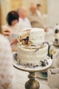 Hands of bride and groom cutting delicious modern cake in restaurant, close up. Beautiful wedding couple holding slice of Royalty Free Stock Photo
