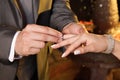 Hands of the bride and groom placing wedding rings