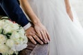 Hands of bride and groom with rings and bouquet of white roses and orchids on the table Royalty Free Stock Photo