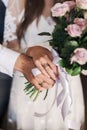 hands of the bride and groom with rings hold the bride's bouquet Royalty Free Stock Photo