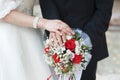 Hands of bride and groom with rings on wedding bouquet of roses Royalty Free Stock Photo