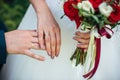 Hands of bride and groom together, close-up. Gold wedding rings on the fingers of newlyweds on the background of a white dress and Royalty Free Stock Photo