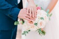 Hands of bride and groom with wedding rings on beautiful bouquet of roses Royalty Free Stock Photo