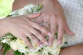 Hands of the bride and groom with wedding rings on a bouquet of flowers Royalty Free Stock Photo