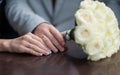 Hands of bride and groom with wedding rings and bouquet of roses Royalty Free Stock Photo