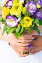 The hands of the bride and groom with wedding rings on their fingers hold together a bouquet of eustoma flowers. Royalty Free Stock Photo