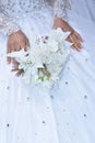 Hands of the bride in a white beautiful wedding dress with a bouquet of delicate flowers. No face, clothing details Royalty Free Stock Photo