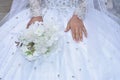 Hands of the bride in a white beautiful wedding dress with a bouquet of delicate flowers. No face, clothing details