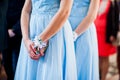 Hands of bridesmaids on blue dresses at wedding