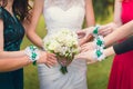 Hands bridesmaids with bracelets stretch to bridal bouquet