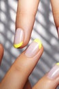 Hands with bright yellow french manicure. Nails art design. Close-up of hands with trendy neon nails on striped print Royalty Free Stock Photo