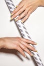 Hands with bright yellow french manicure. Nails art design. Close-up of hands with trendy neon nails on striped print