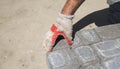 Hands of a builder in his orange gloved hands fitting laying new exterior paving stones carefully placing one in Royalty Free Stock Photo