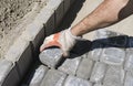 Hands of a builder in his orange gloved hands fitting laying new exterior paving stones carefully placing one in Royalty Free Stock Photo