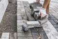 Hands of a builder in his orange gloved hands with a hammer fitting laying new exterior paving stones carefully placing Royalty Free Stock Photo