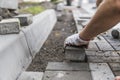 Hands of a builder in his orange gloved hands with a hammer fitting laying new exterior paving stones carefully placing Royalty Free Stock Photo