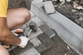 Hands of a builder in his orange gloved hands with a hammer fitting laying new exterior paving stones carefully placing Royalty Free Stock Photo