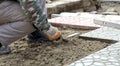 Hands of a builder laying new paving stones carefully placing one in position on a leveled and raked sand base Royalty Free Stock Photo