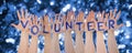 Hands Building Word Volunteer, Glittering And Sparkling Bokeh Background