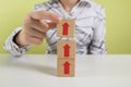 Hands of a business woman stack wooden blocks with an arrow up. Ladder career path concept for successful business development