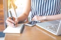 The hands of a business woman working at a computer and writing Royalty Free Stock Photo