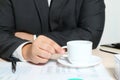 Hands of businessman with cup of coffee at table