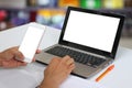 Hands of a businessman holding an empty smartphone and have blank notebook Laptop have white screen. Royalty Free Stock Photo