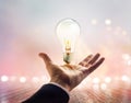 Hands of a businessman reaching to towards light bulb on wooden Royalty Free Stock Photo