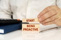 In the hands of a businessman, wooden blocks with the inscription - Start Being Proactive