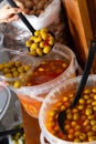 Hands of buyer pouring pickled olives by weight into plastic container