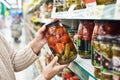 Hands with can of salted tomatoes and cucumbers in store