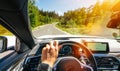 Hands of car driver on steering wheel, road trip, driving on highway road