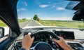 Hands of car driver on steering wheel, road trip, driving on highway road