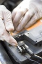 The hands of the car mechanic in disposable gloves unscrew the battery clutch.
