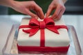 hands carefully placing a fondant bow on a gift box cake Royalty Free Stock Photo