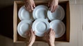 hands carefully stacking plates into a cardboard moving box, illustrating the meticulous process of packing and securing