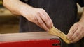 Hands of carpenter sharpens wooden part on grinding machine. Handwork concept, woodworking workshop. Royalty Free Stock Photo
