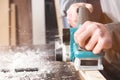 The hands of a carpenter working woodworking power tools. Close up of the work of the electric planer