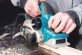 The hands of a carpenter working woodworking power tools. Close up of the work of the electric planer