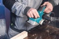 The hands of a carpenter working woodworking power tools. Close up of the work of the electric planer