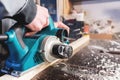 The hands of a carpenter working woodworking power tools. Close up of the work of the electric planer