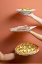 Hands carrying plates with meat tomahawk steak, italian pasta nand cheese pizza. Creative idea, plated in hands Royalty Free Stock Photo