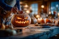 Hands carve intricate scary face into pumpkin with candle light illuminating the design. Kitchen setting features rustic Royalty Free Stock Photo