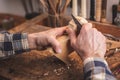 Hands carving a small piece of wood on a workbench