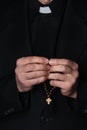 Hands of catholic priest holding rosary