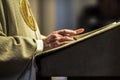 Hands of catholic priest reading a bible.