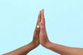 Hands of Caucasian and black African American women giving each other five on blue background. The concept of racism and